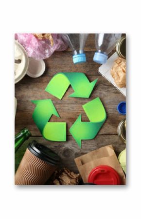 Recycling symbol and different garbage on wooden background, top view