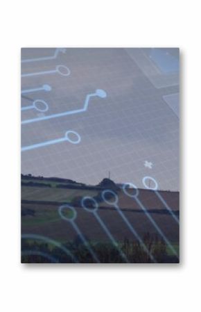 Standing wind turbine overlooking fields with hedgerows and trees on hill with circuit overlay