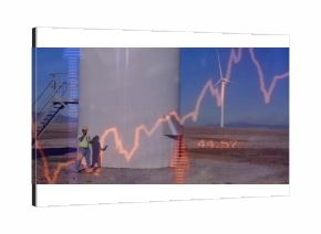 Wind farm technician with helmet reviewing graph and talking on phone at turbine base, copy space