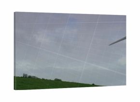 Standing wind turbine on hillside with grassy ridge, shrubs and grid overlay, copy space