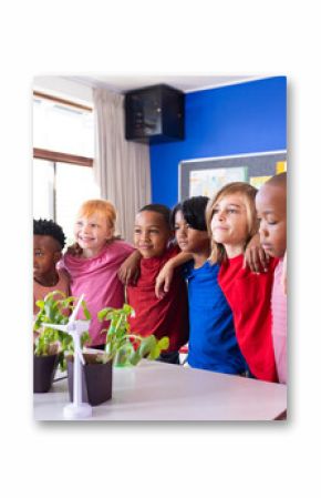 In school, diverse group of children standing together, smiling near wind turbines