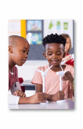 In school, diverse children studying wind turbines and renewable energy in classroom