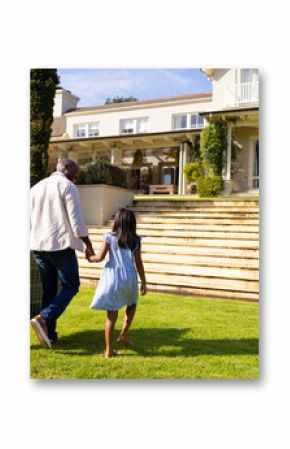 Carrying solar panel, father and daughter walking towards house on sunny day