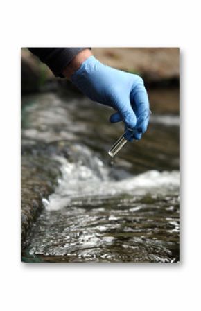 Water sample. Gloved hand into the water collecting tube. Analysis of water purity, environment, ecology - concept. Water testing for infections, harmful emissions