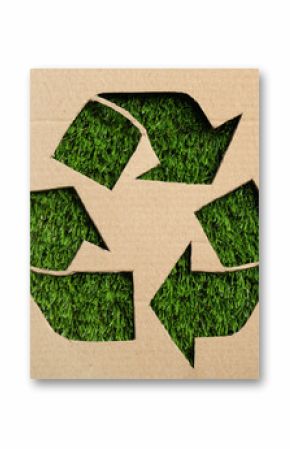 Sheet of cardboard with cutout recycling symbol on green grass, top view