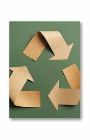 Recycling symbol cut out of kraft paper on green background, top view