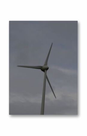 Lone wind turbine generating electricity in open rural landscape, under overcast sky