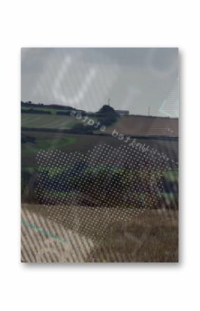 Turbine rising over meadow, hedgerow shrubs in farmland, with digital overlay patterns, copy space