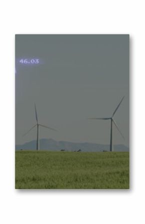 Three wind turbines spinning in green crop field, with two upward arrows labeled 46