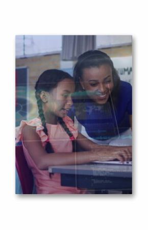 Teacher in blue top guiding student typing on laptop in classroom, with climate change poster
