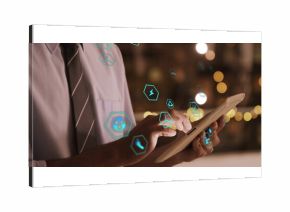 Man in shirt and tie viewing green energy icons in office at night, with white tablet