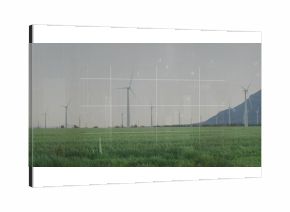 Towering central wind turbine rising above green crop field, with distant mountain ridge