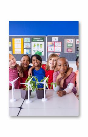 In school, group of diverse children smiling around table with wind turbines