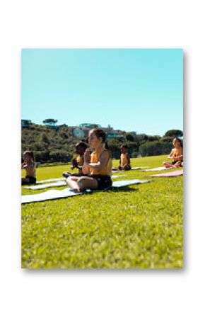 Diverse schoolgirls meditate in prayer pose on grass, clear sky above