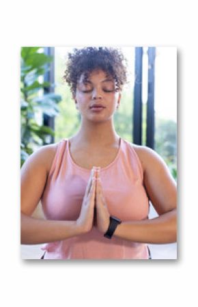 Meditating with hands in prayer position, plus size woman practicing mindfulness, at home, at home