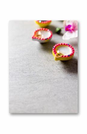 Close up of three diwali candles and flowers with copy space on grey background