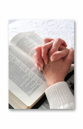 Female hands clasped in prayer ove a Bible