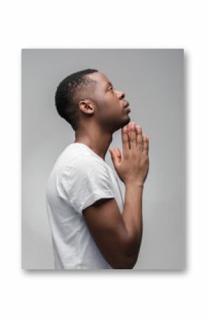 Praying african american man hoping for better. Asking God for good luck, success, forgiveness. Power of religion, belief, worship. Holding hands in prayer, looking up.