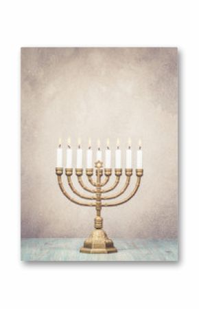 Bronze Hanukkah menorah with burning candles on wooden table front old vintage concrete wall background. Holiday greeting card concept. Retro style filtered photo