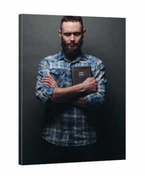 Handsone man reading and praying over Bible in a dark room over gray texture
