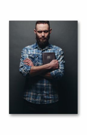 Handsone man reading and praying over Bible in a dark room over gray texture