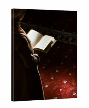 Muslim woman under the sunlight reading quran in a mosque