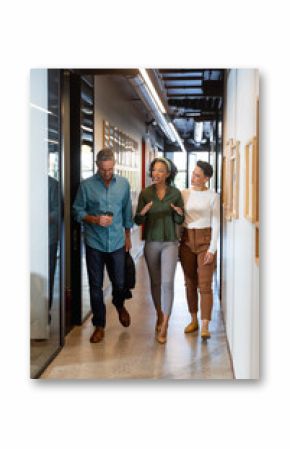 Multiracial businessman and businesswomen discussing while walking in corridor of office building