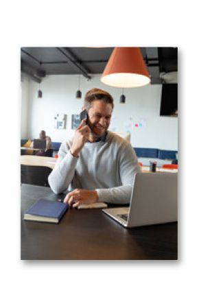Smiling caucasian mid adult businessman talking on mobile phone in creative office