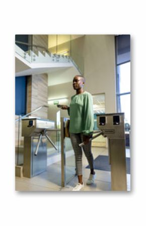 African american businesswoman with short hair entering from turnstile gate in office, copy space
