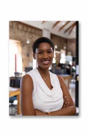 Portrait of happy african american casual businesswoman with arms crossed in creative office