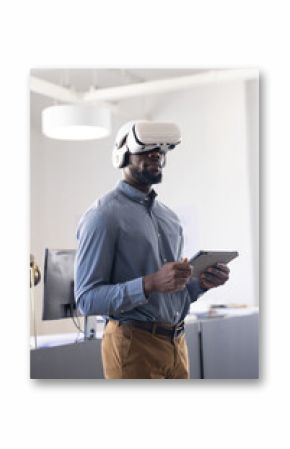 Using VR headset, businessman holding tablet and exploring virtual reality in office