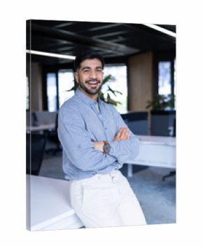 Smiling businessman in modern office, standing with arms crossed confidently