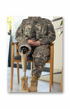Military soldier personnel with prosthetic leg sitting on chair, wearing camouflage uniform
