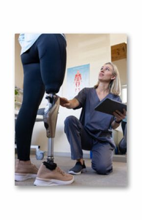 Therapist examining prosthetic leg while holding tablet in rehabilitation center