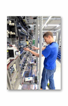 Montage von Elektronik in einer Fabrik - junger Mann arbeitet an einem Schaltschrank // Montage of electronics in a factory