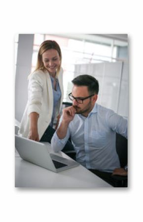 Two business people watching something on laptop. Business woman showing something to colleague in laptop.