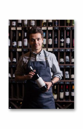 Portrait of a sommelier standing in a wine cellar holding a glass of wine and showing thumb up, during a degustation