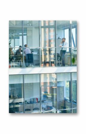 Wide angle portrait of mature businessman speaking by phone standing behind floor to ceiling windows in modern office building, copy space