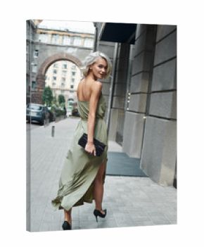 Fashion. Young stylish woman walking on the city street looking back smiling playful full body shot