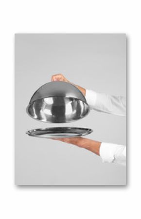 Waiter holding metal tray with lid on grey background