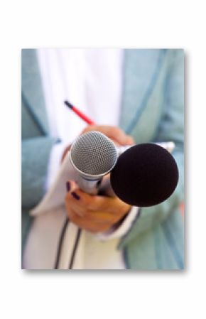 Female journalist at news conference, writing notes, holding microphone