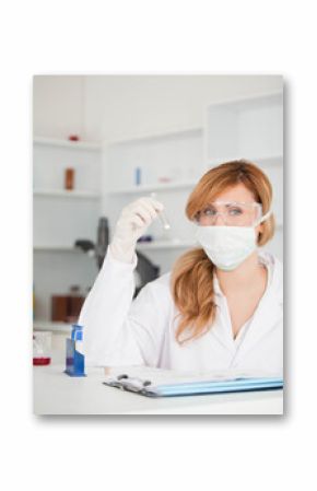 Scientist inspecting swab at eye level on lab bench with clipboard, tube rack and red beaker