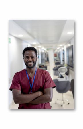 Smiling healthcare professional in scrubs standing confidently in hospital corridor
