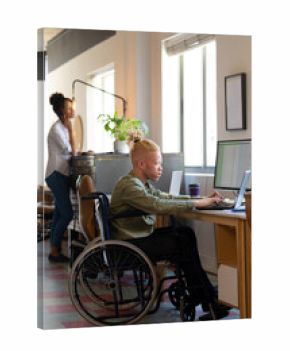 African american disable albino mid adult businessman on wheelchair using laptop at desk in office