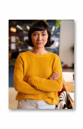Portrait of confident biracial young businesswoman standing with arms crossed in office