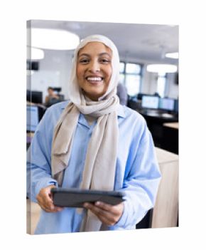 Vertical image of happy middle-eastern businesswoman in hijab looking at camera in office