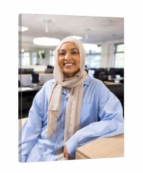 Vertical image of happy middle-eastern businesswoman in hijab looking at camera in office