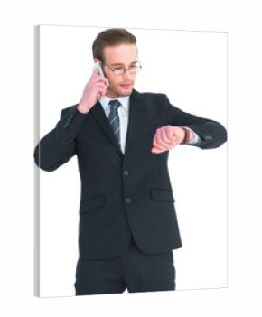 Serious businessman phoning while checking time
