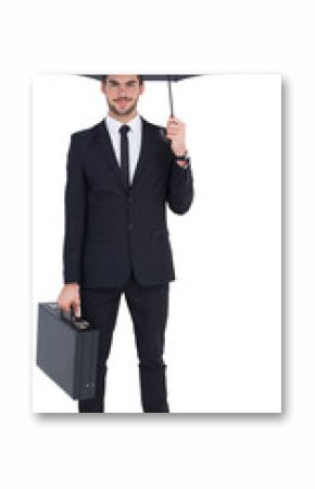 Smiling businessman under umbrella while holding briefcase