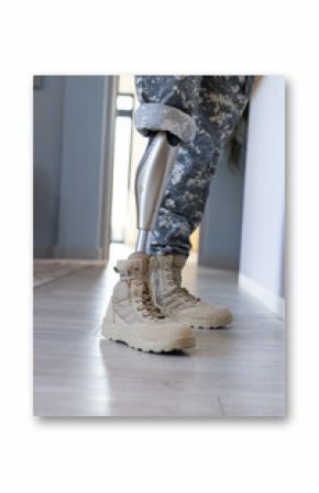 Military soldier personnel with prosthetic leg wearing camouflage pants and boots indoors